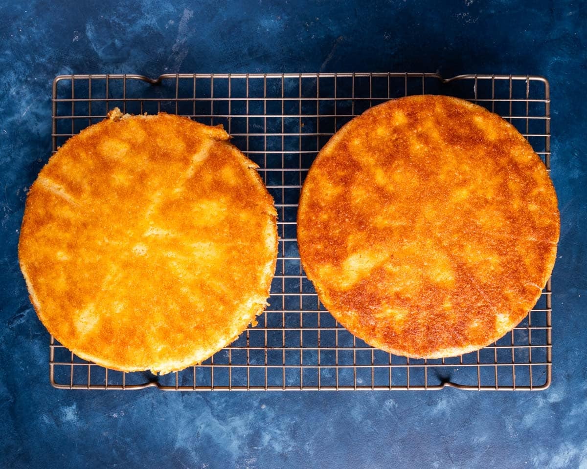 overhead view of two yellow cakes on a wire rack