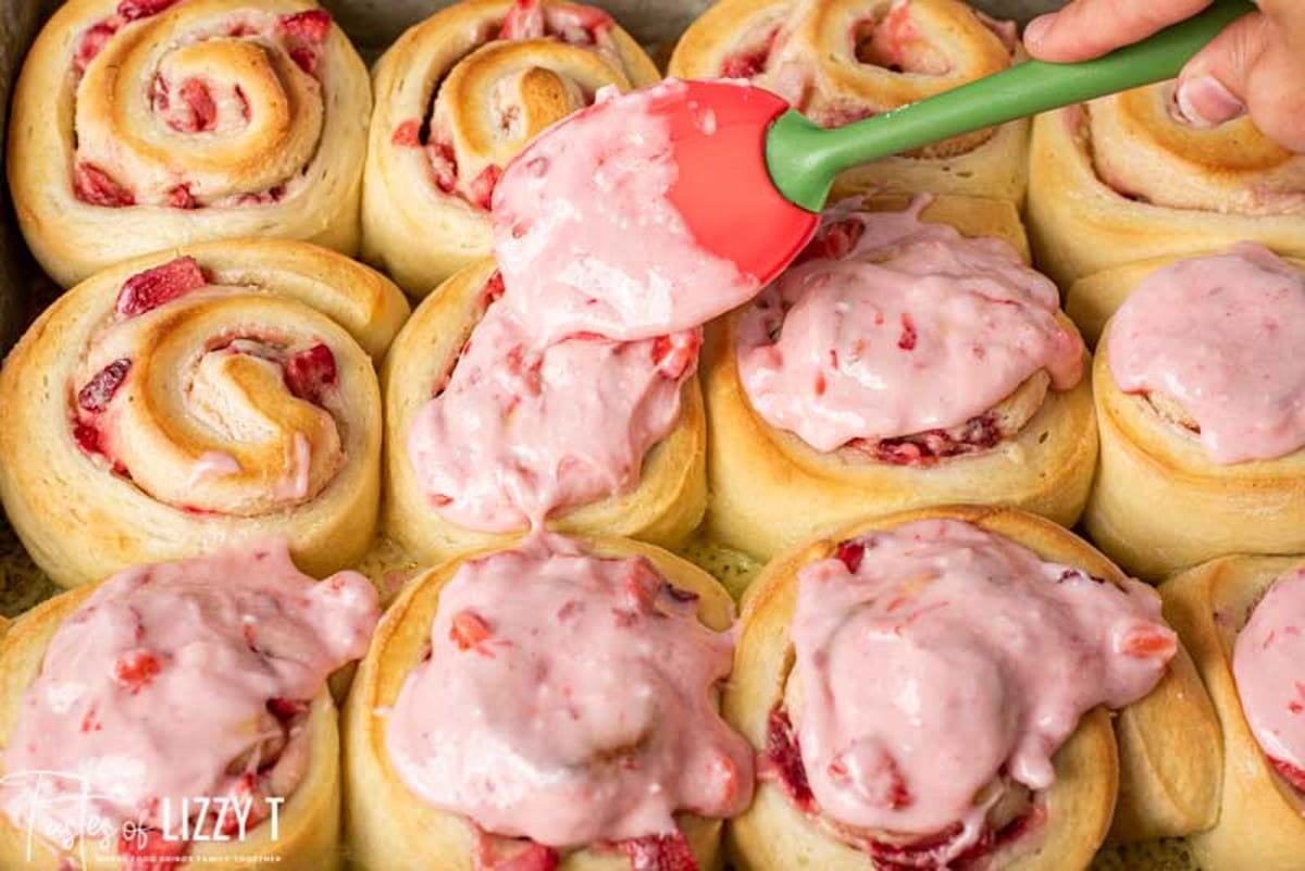 spreading strawberry frosting on sweet rolls