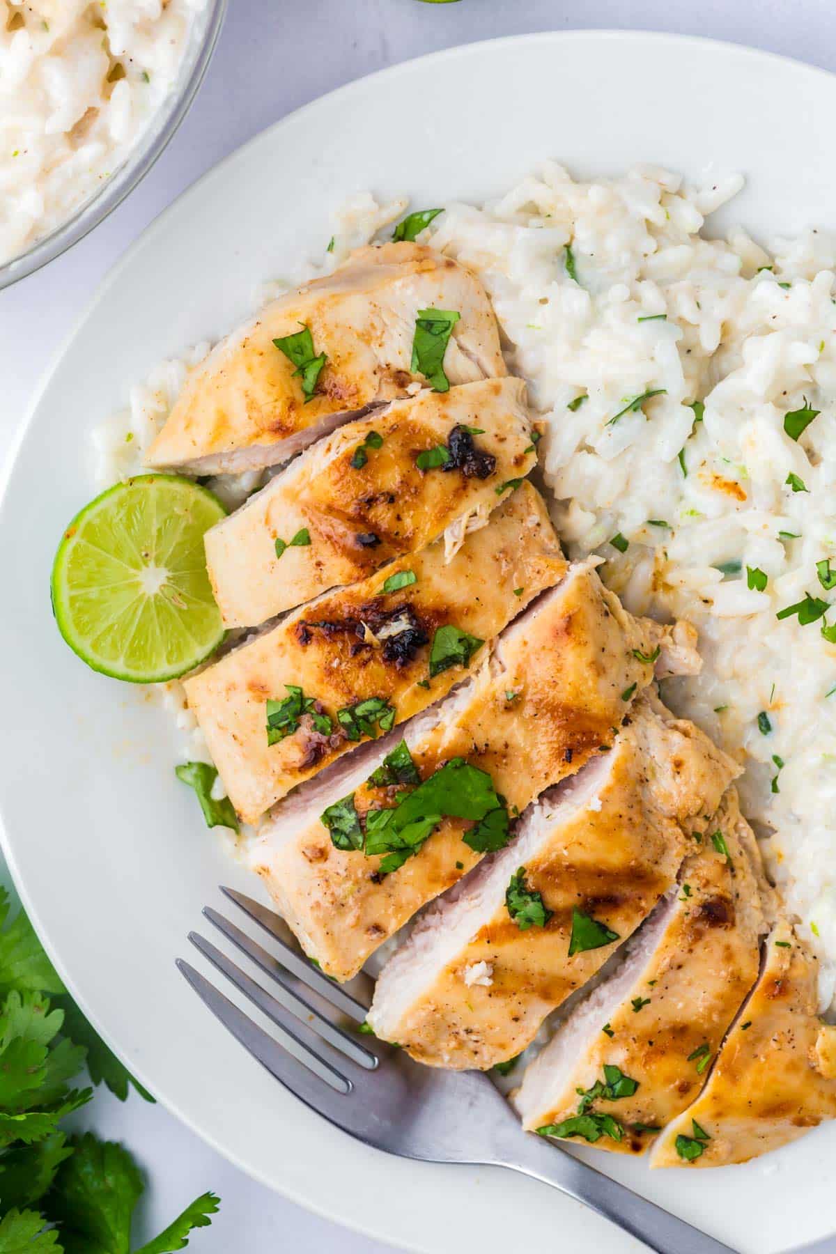 a sliced coconut lime chicken breast with rice on a plate