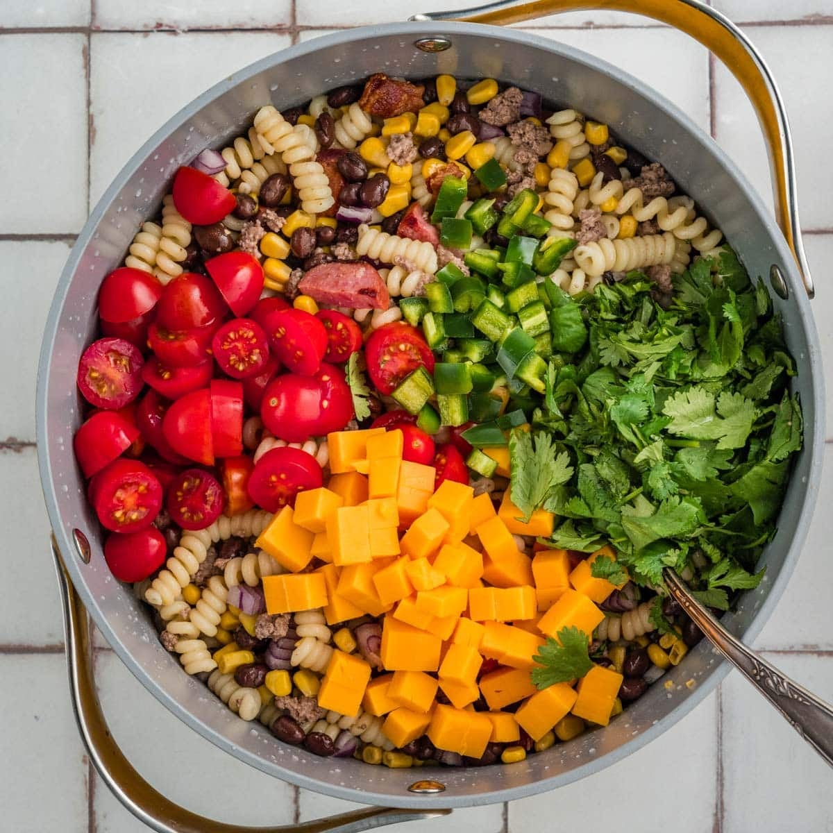tomatoes, cheese, cilantro and pepper over pasta mixture in a saucepan