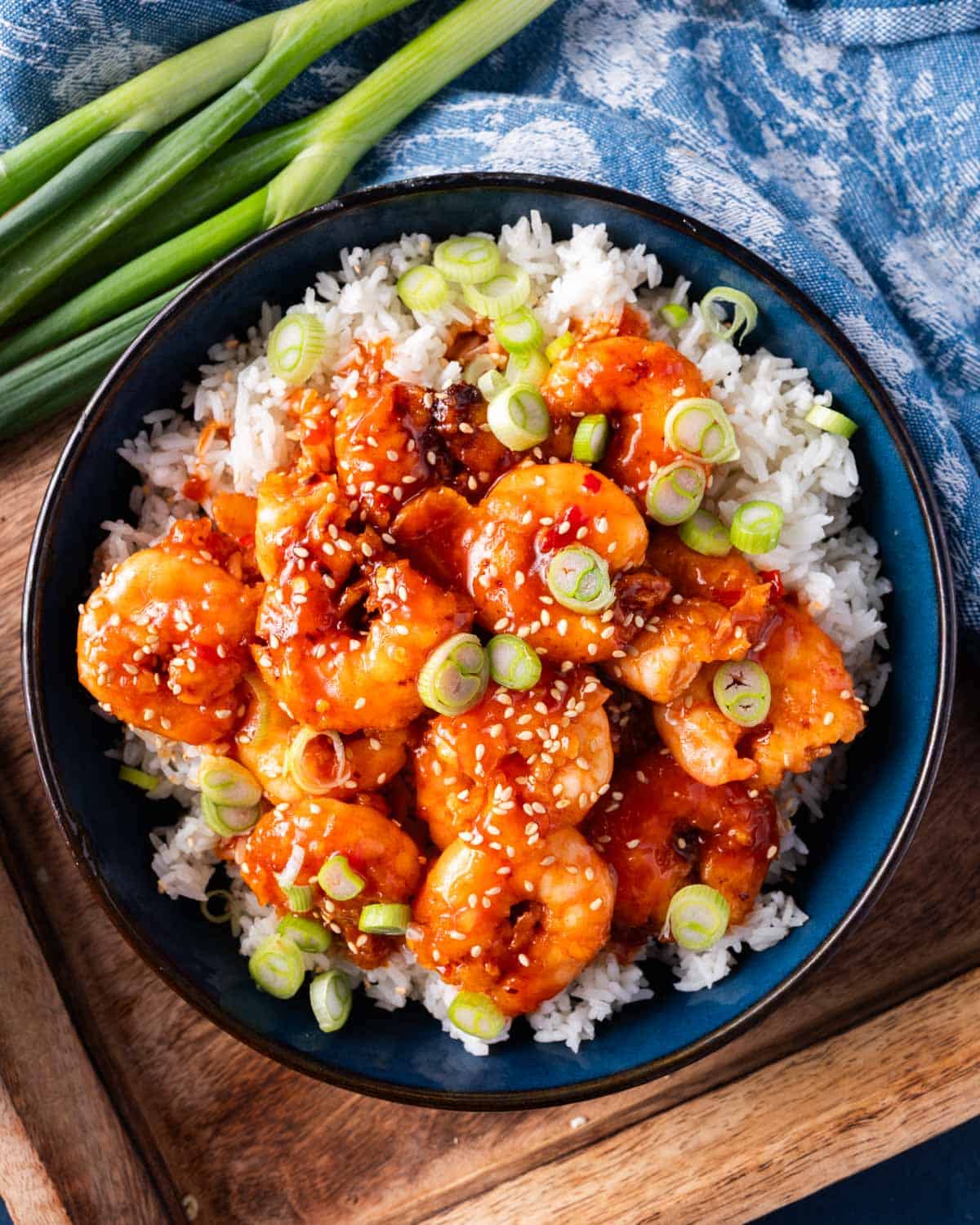 a plate of firecracker shrimp with rice and green onions