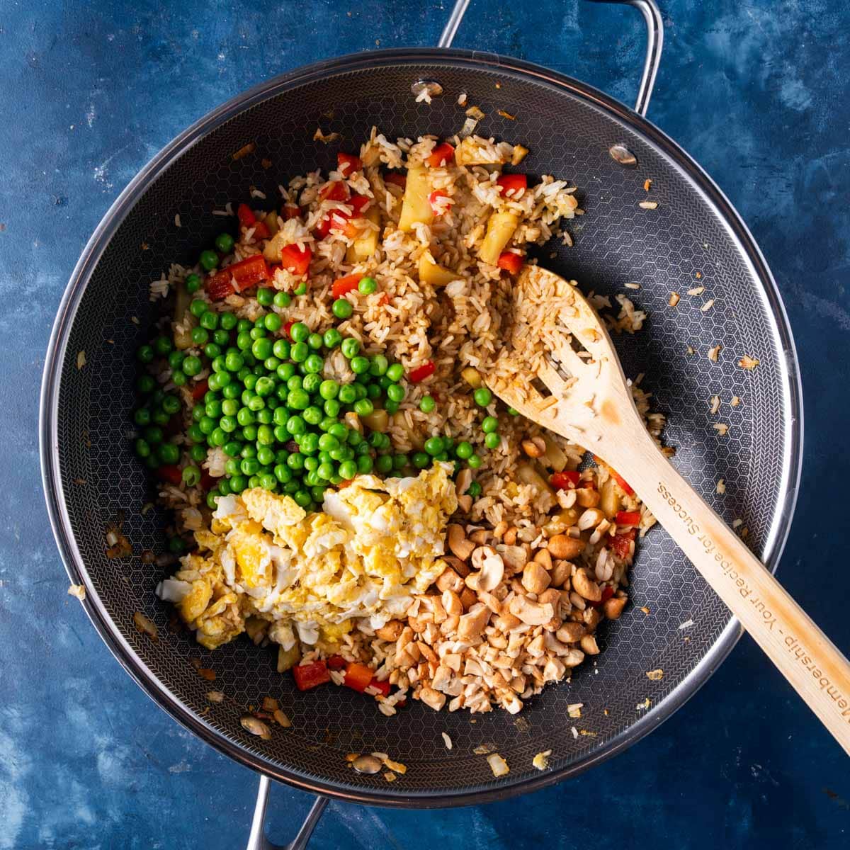 fried rice with peas, eggs and cashews in a pan