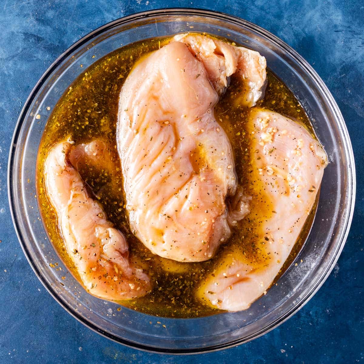 chicken breasts marinating in a bowl
