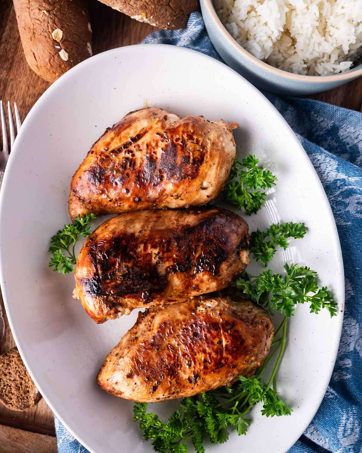 three marinated chicken breasts on a white plate