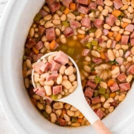 slow cooker ham and beans with a ladle