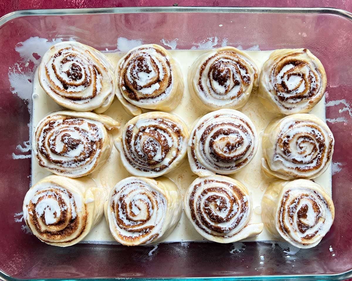 unbaked cinnamon roll in a pan with heavy cream on top
