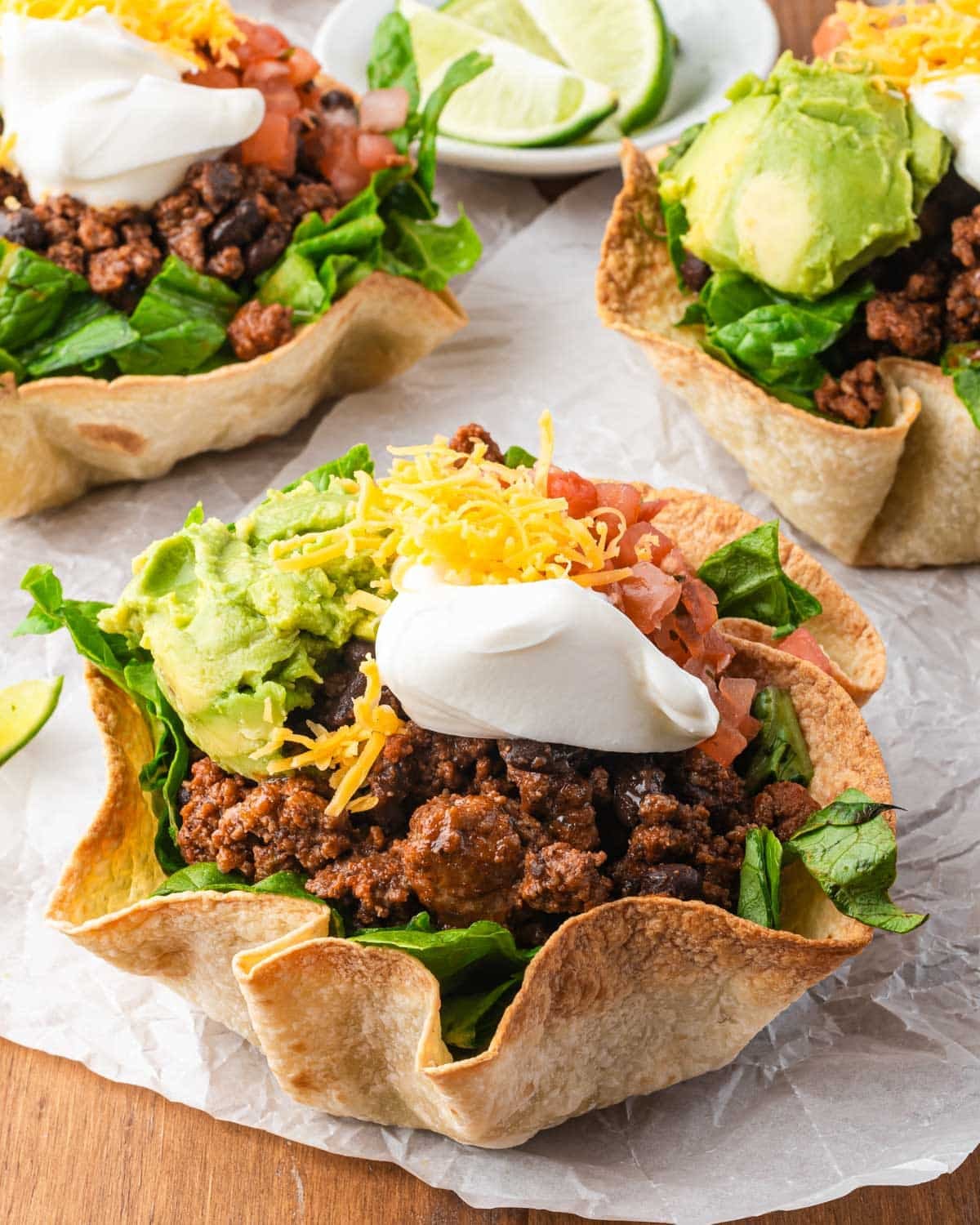 a taco bowl with avocado, cheddar cheese and sour cream