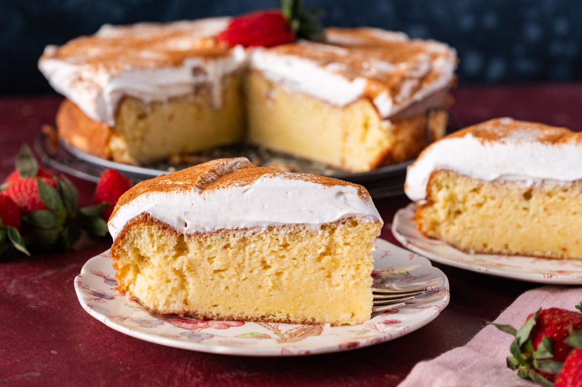 tres leches cake on plates with whipped cream and cinnamon