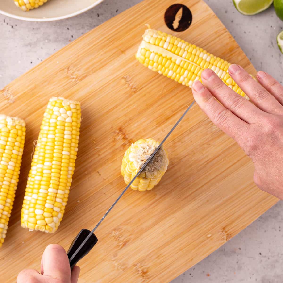 a knife cutting a corn cob down the center