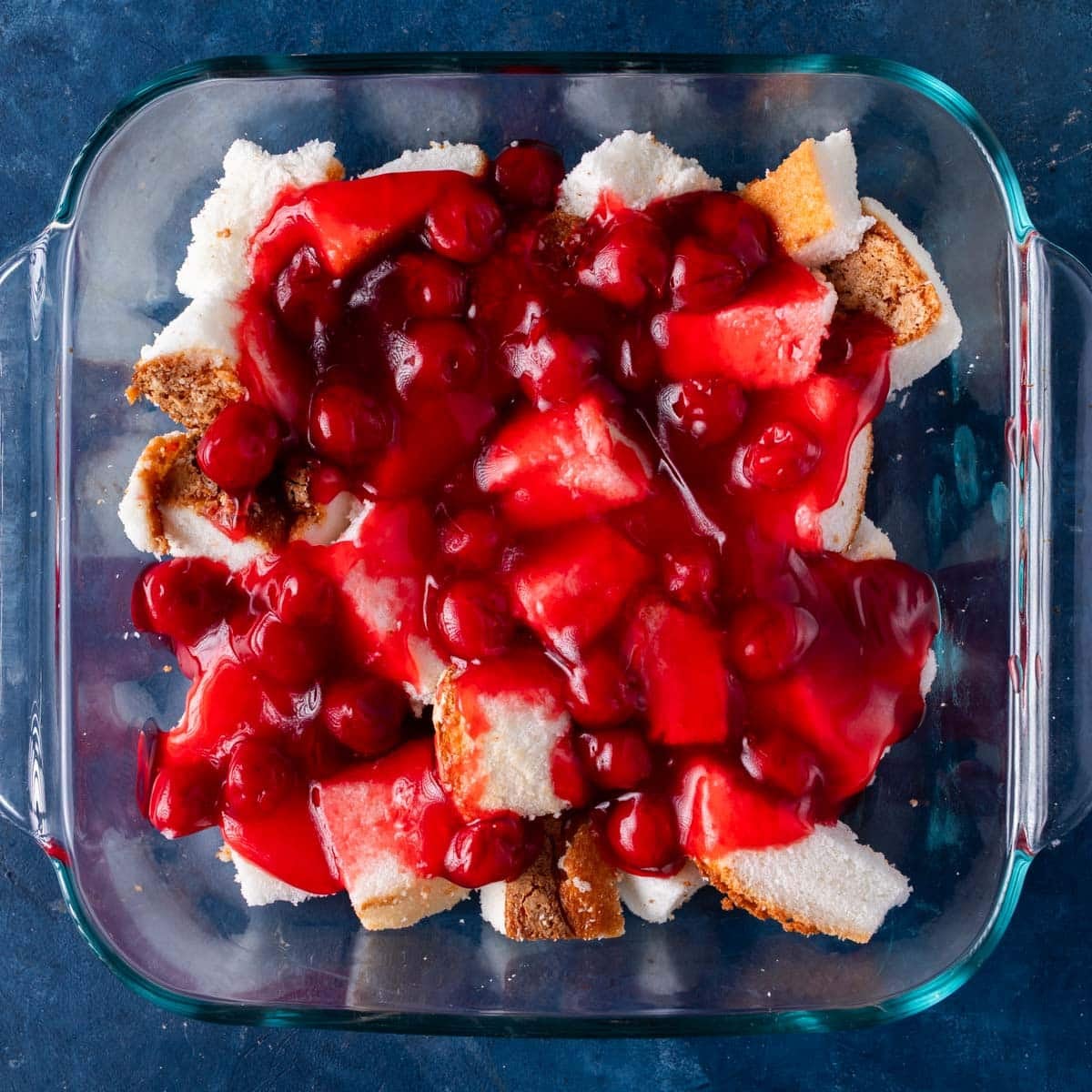 cherry pie filling over angel food cake cubes in a pan