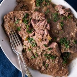 fork tender round steak with mushroom sauce on a plate with two forks