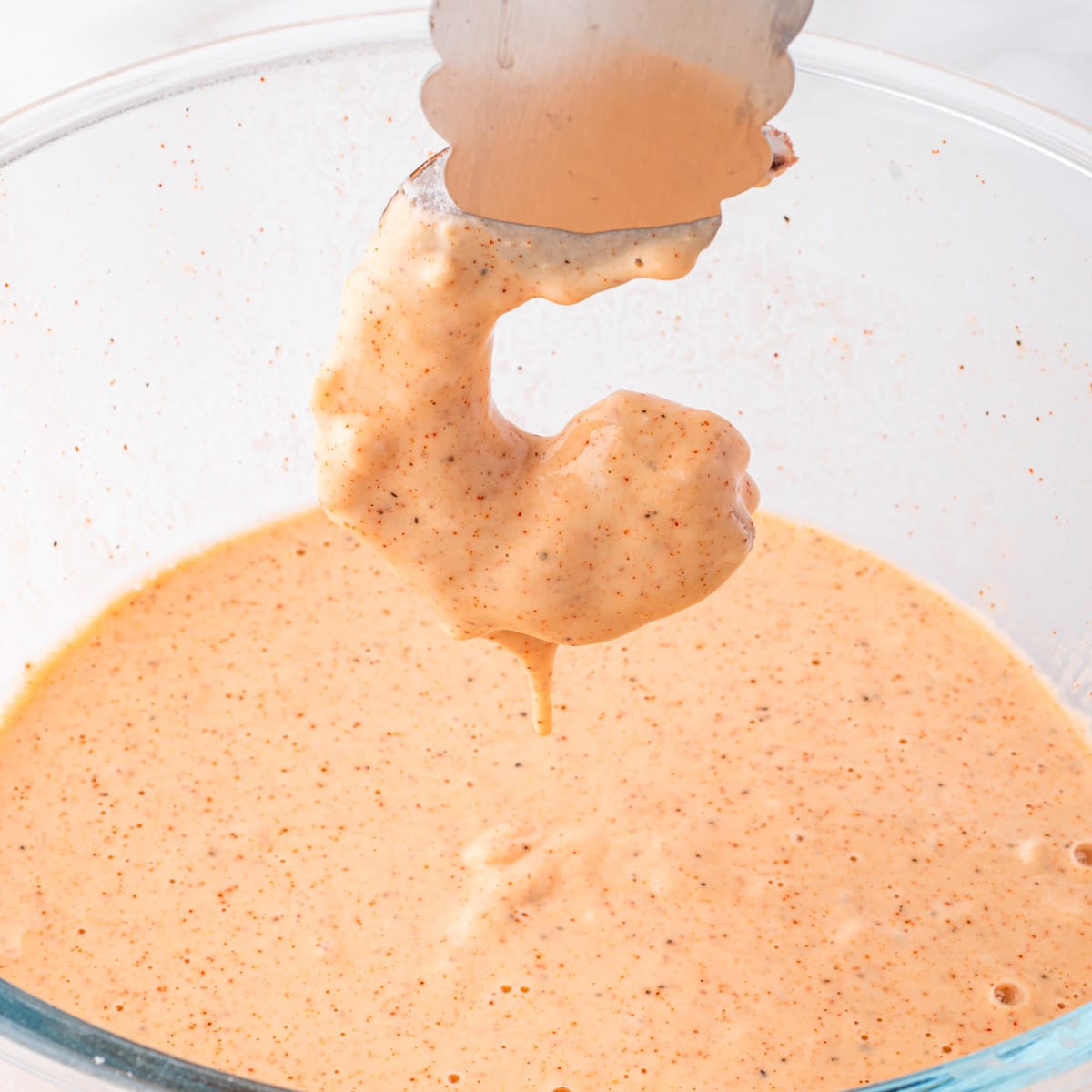 dipping a shrimp into seasoned batter