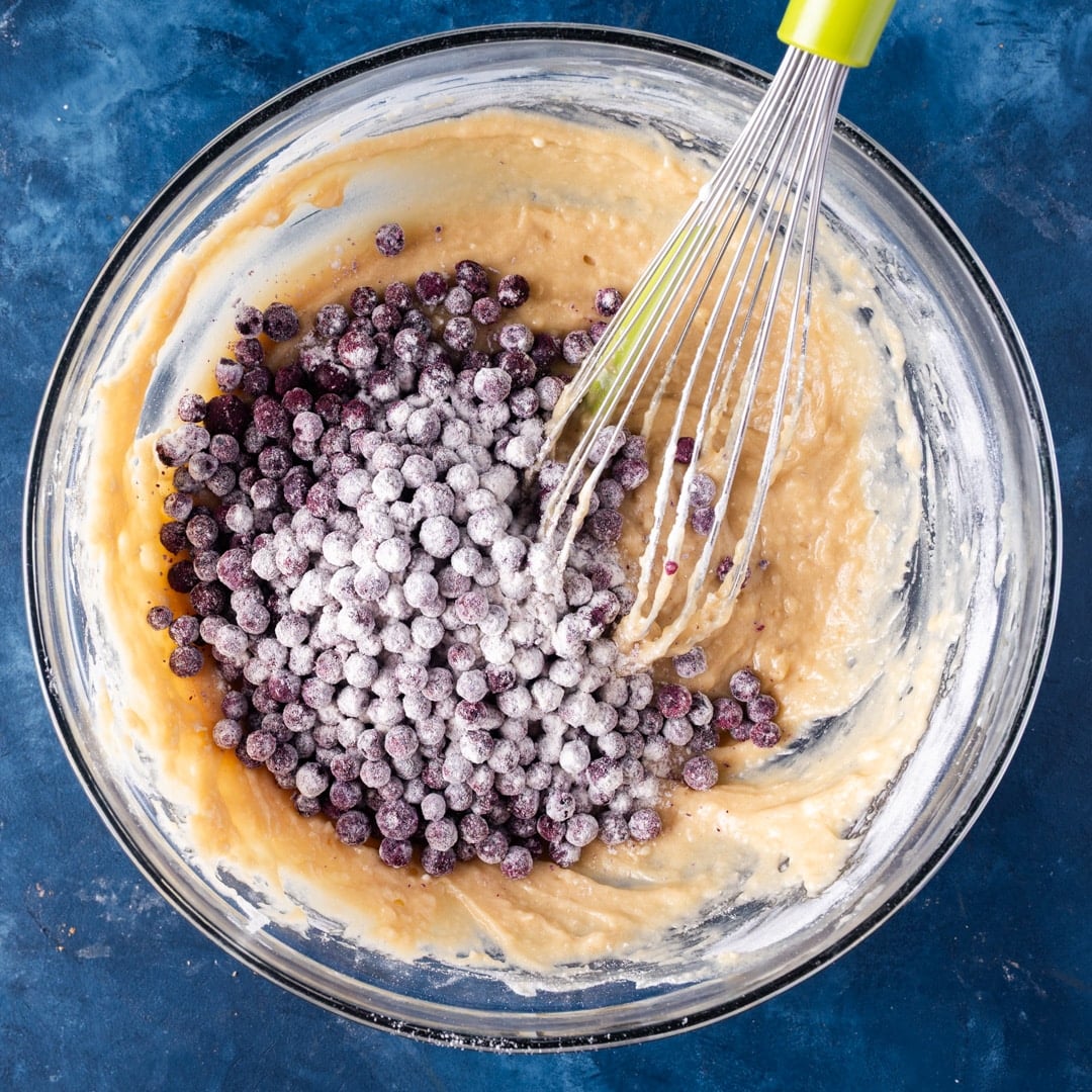 wild blueberries getting mixed into batter in a bowl