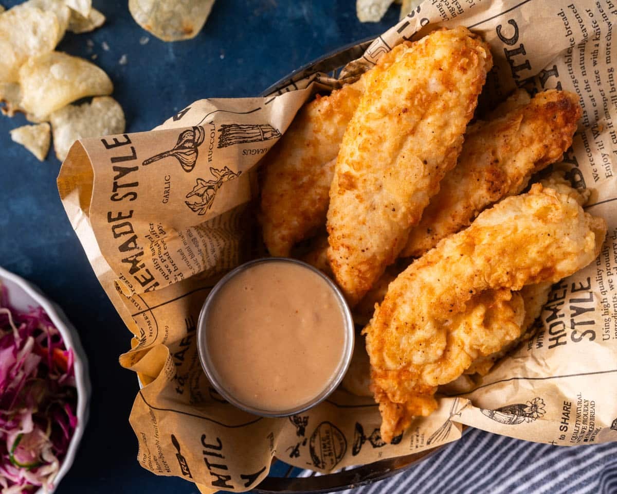 a platter of fried chicken tenders with dipping sauce