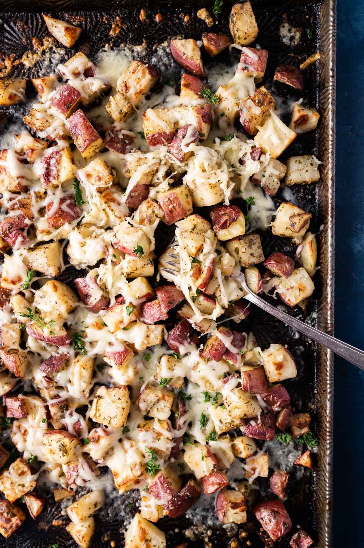 overhead view of oven roasted cheesy potatoes on a pan