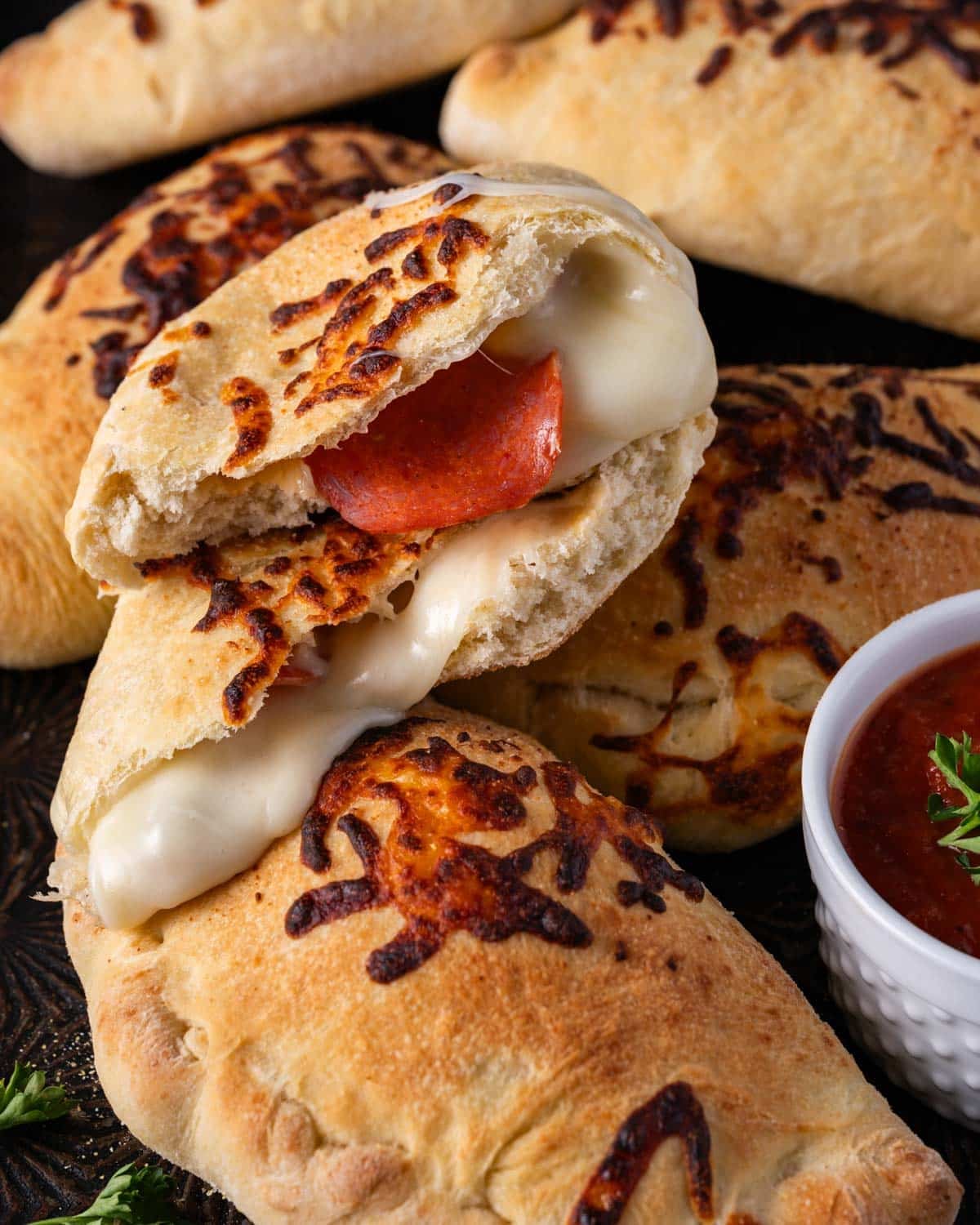 cheese and pepperoni calzones on a baking sheet