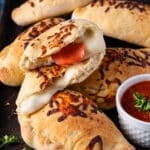 cheese and pepperoni calzones on a baking sheet