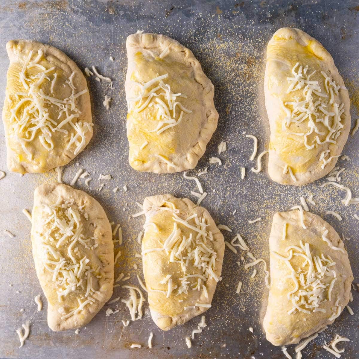 unbaked pepperoni calzones on a baking sheet