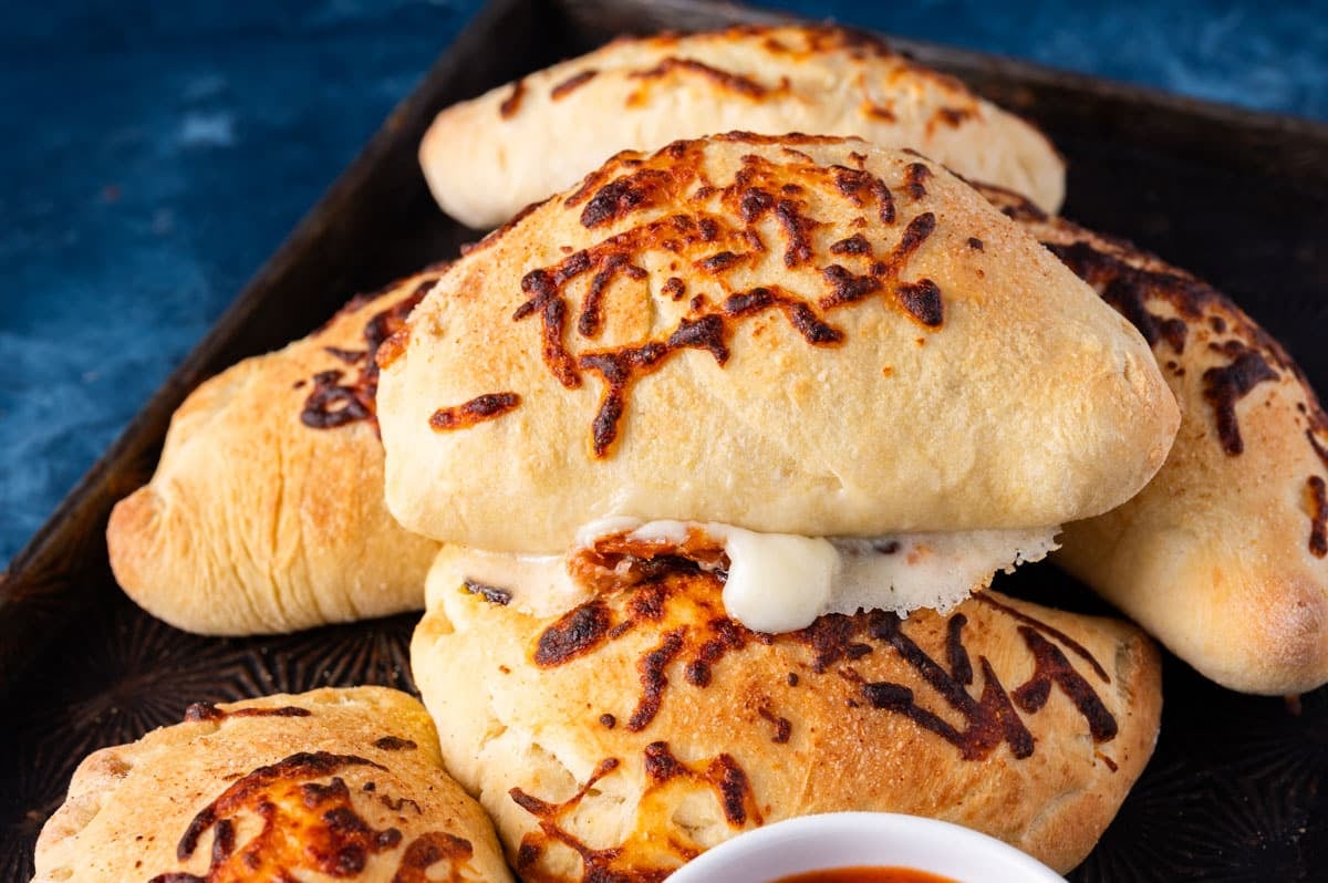 a pile of baked pepperoni calzones