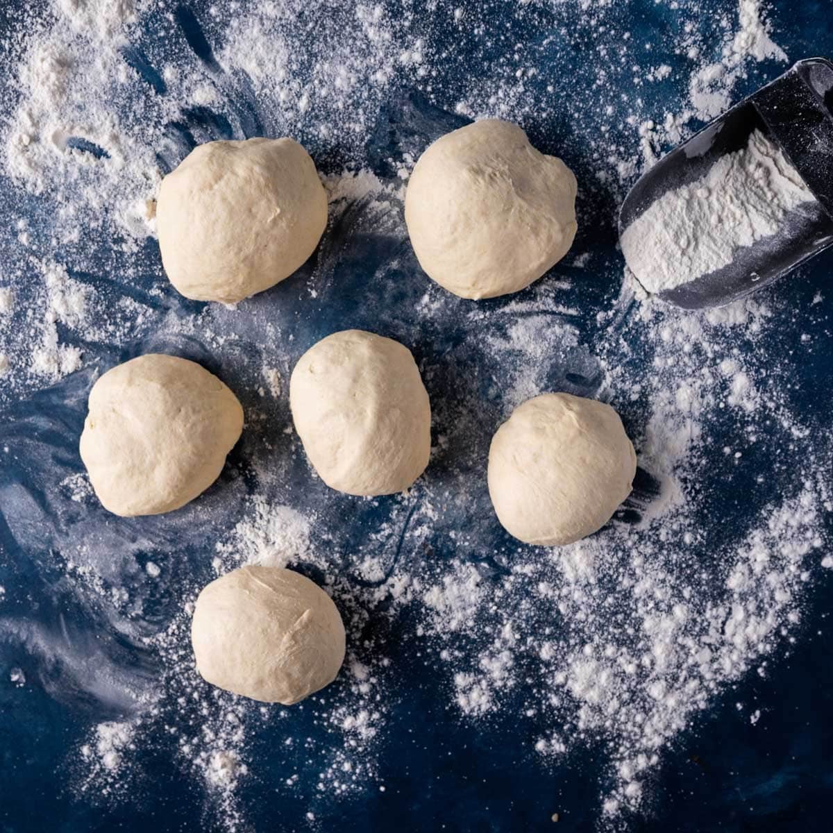 pizza dough balls on a floured surface