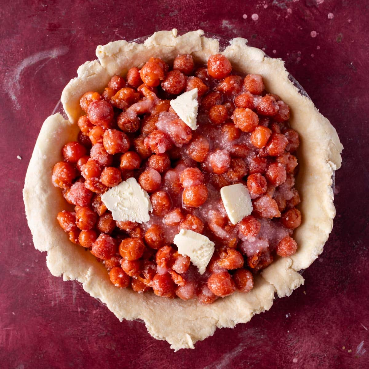 open faced unbaked cherry pie with slices of butter on top