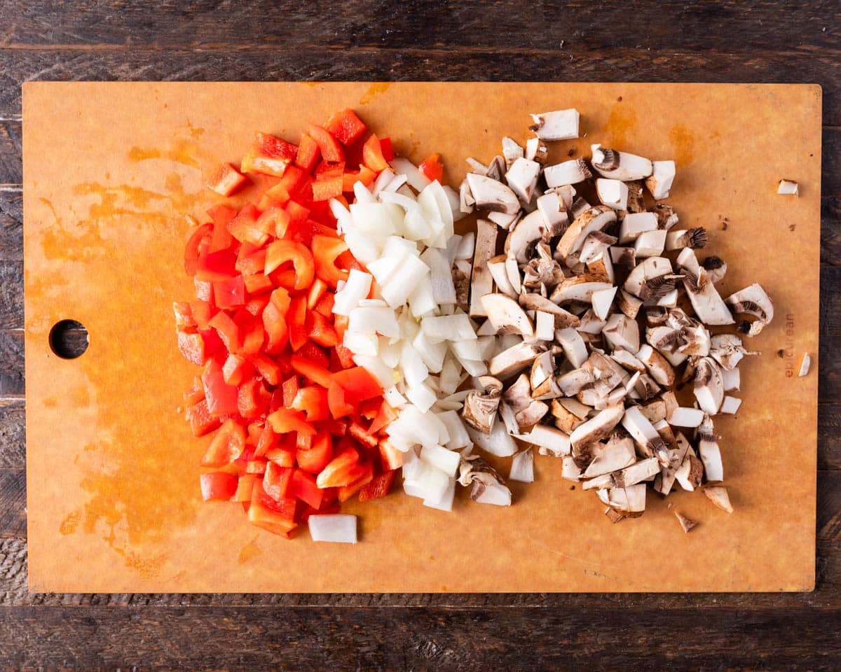 diced peppers, onions and mushrooms on a cutting board