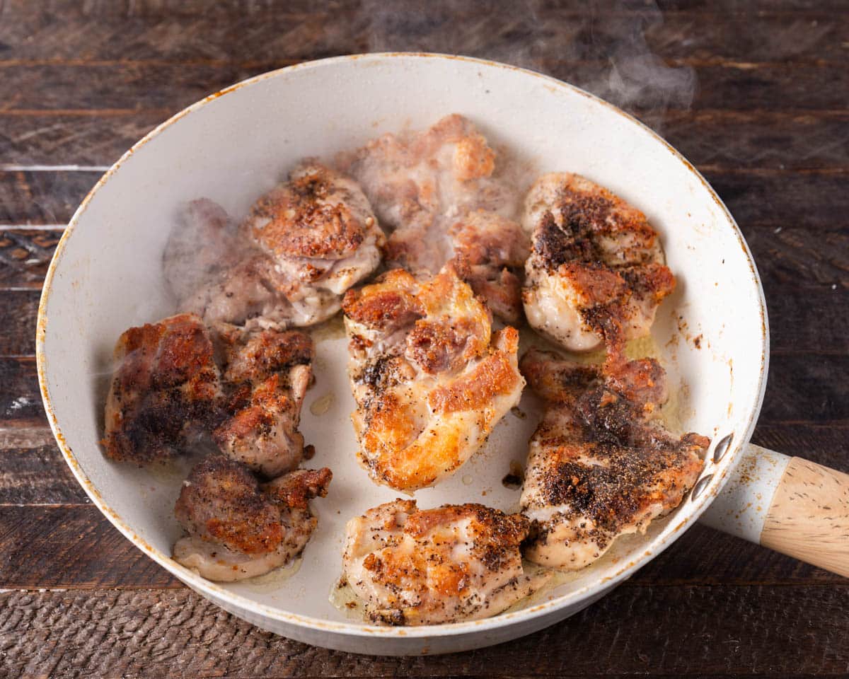 chicken thighs searing in a skillet