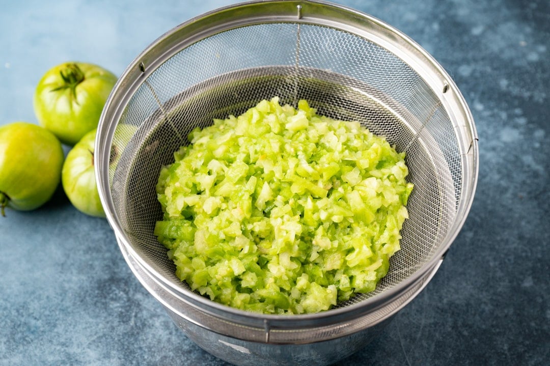 shredded green tomatoes draining in a colander