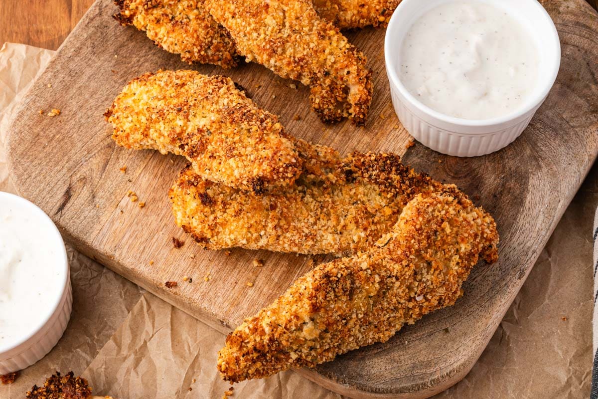 chicken tenders on a cutting board with a bowl of dip