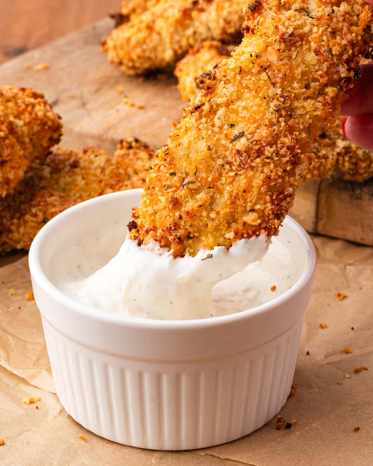 a crispy oven baked chicken tender dipping in yogurt dip