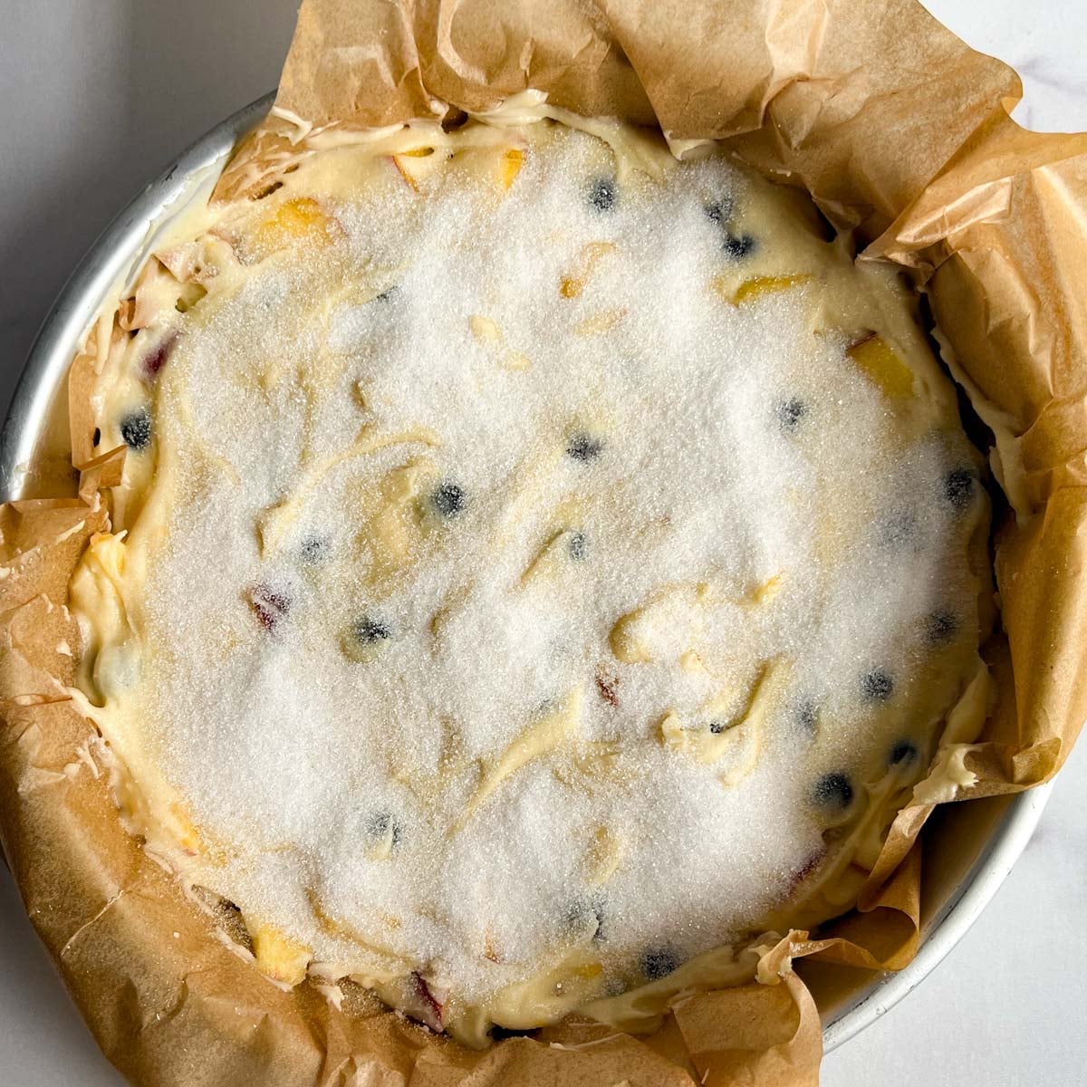 unbaked cake with sugar on top in a round pan