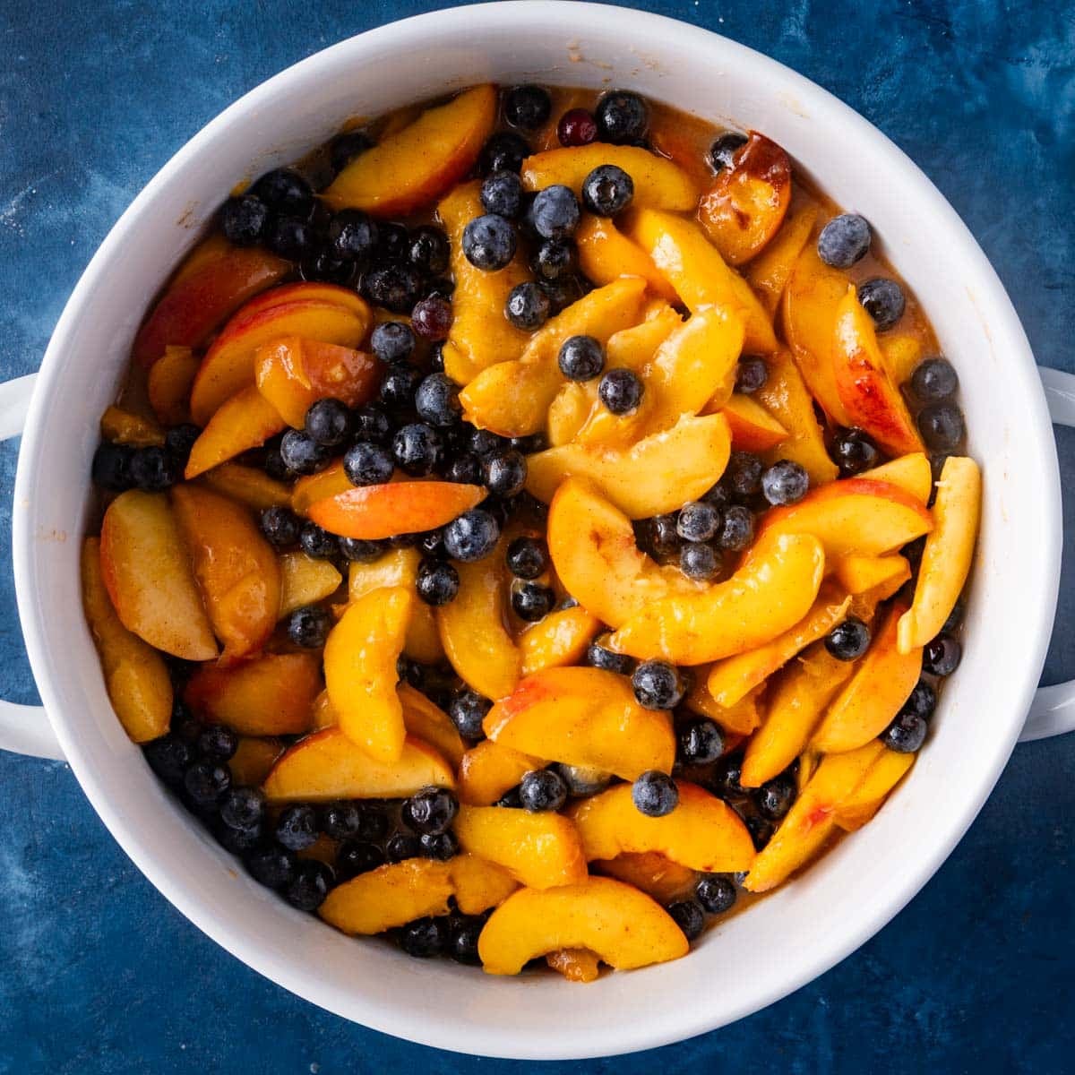 sliced peaches and blueberries in a baking pan