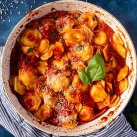ravioli al pomodoro in a skillet with cheese and basil