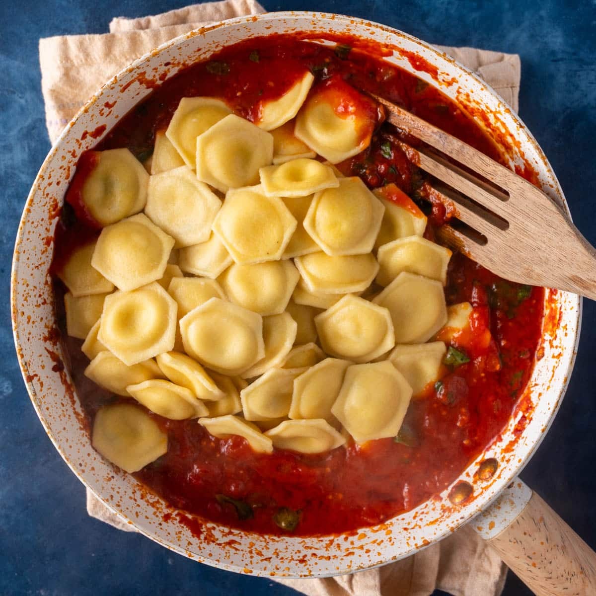 cooked ravioli over tomato sauce in a pan