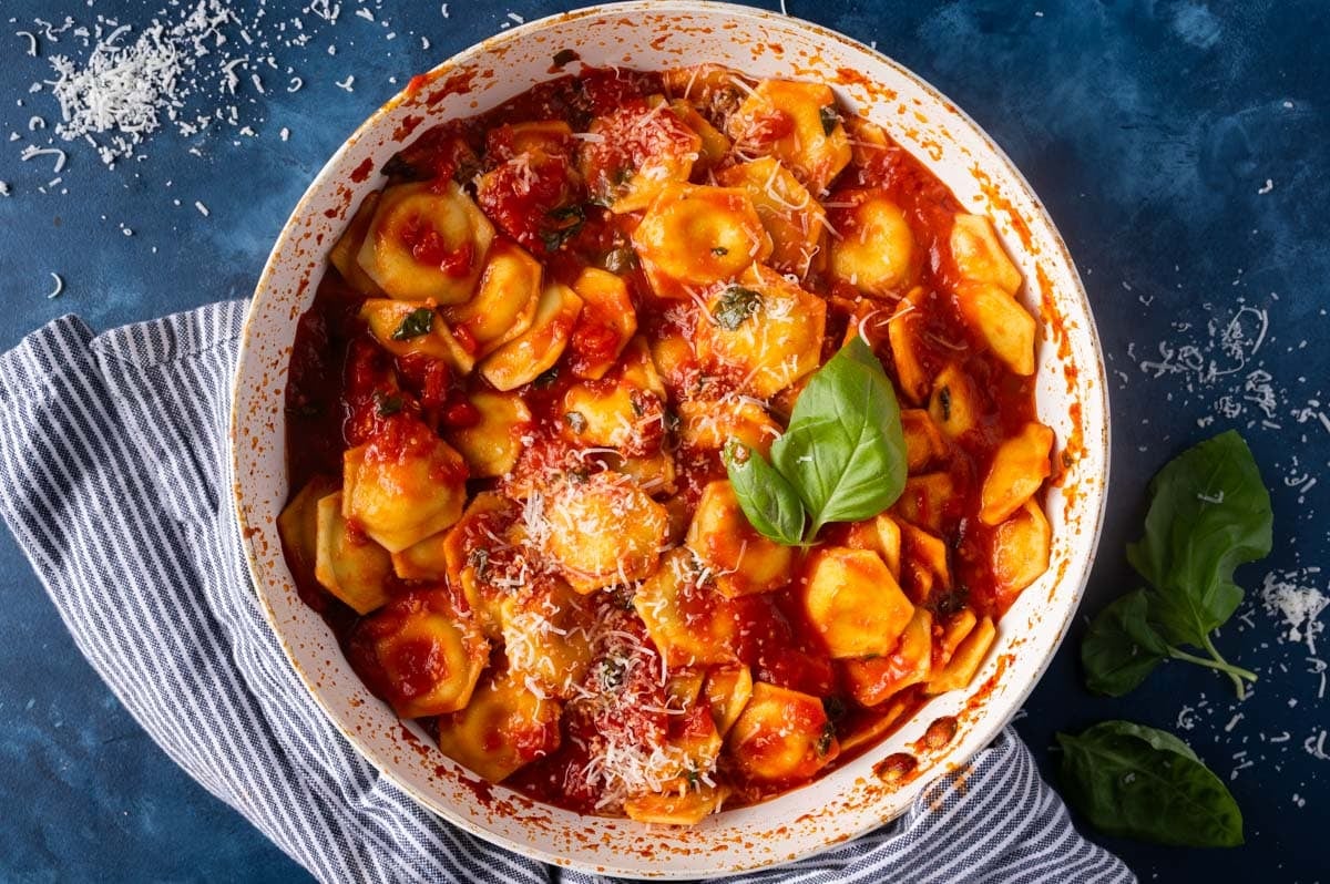 ravioli al pomodoro in a skillet with fresh basil