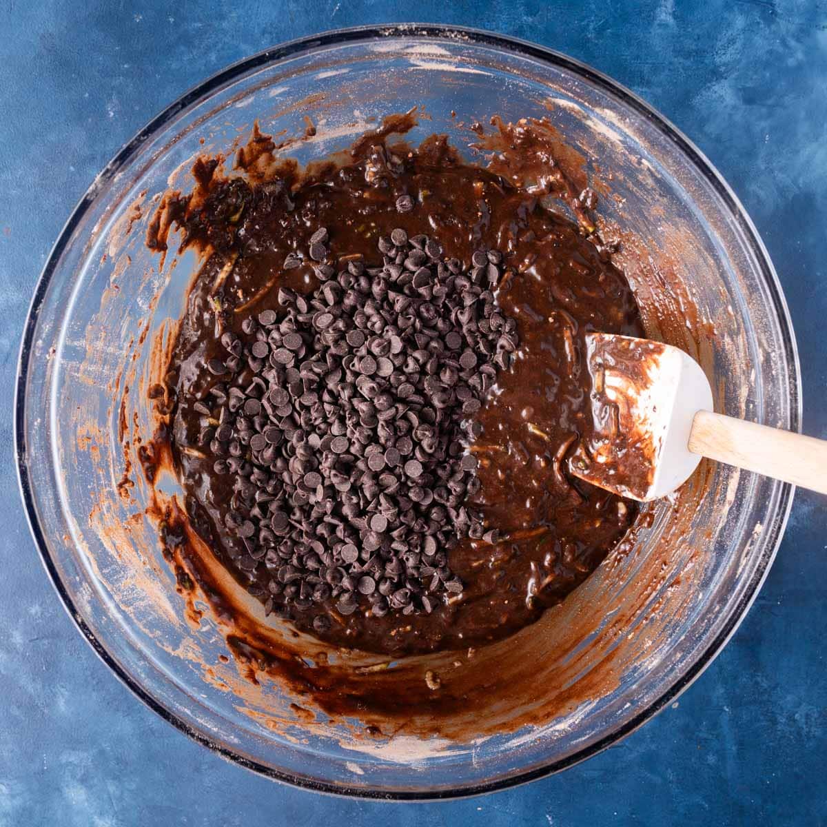 chocolate chips over muffin batter in a bowl