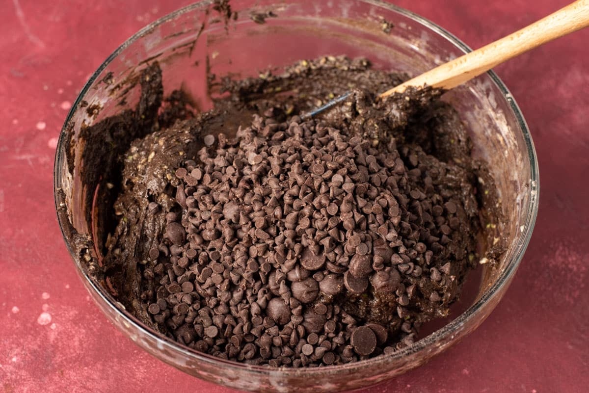 chocolate chips on top of zucchini cake batter in a bowl
