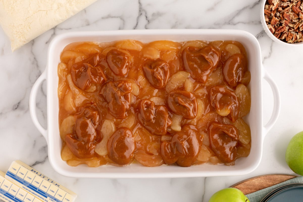 caramel over apple slices in a baking pan