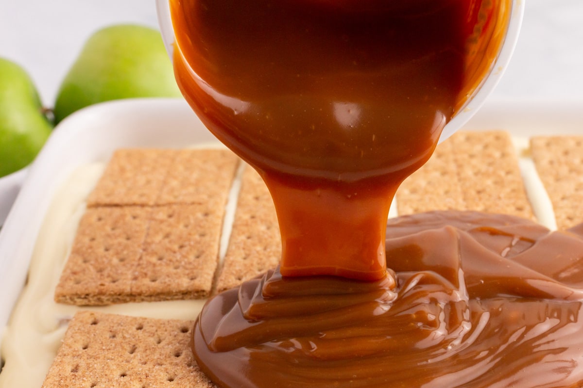 caramel pouring over graham cracker dessert in a pan