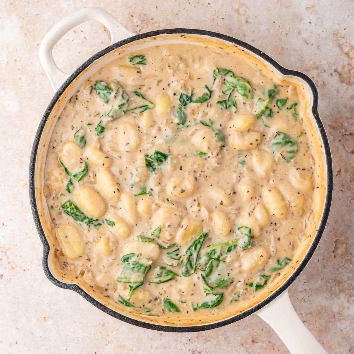 gnocchi and spinach in a cream sauce in a skillet