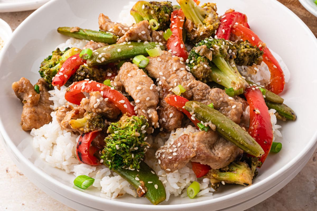 a plate of pork stir fry with rice