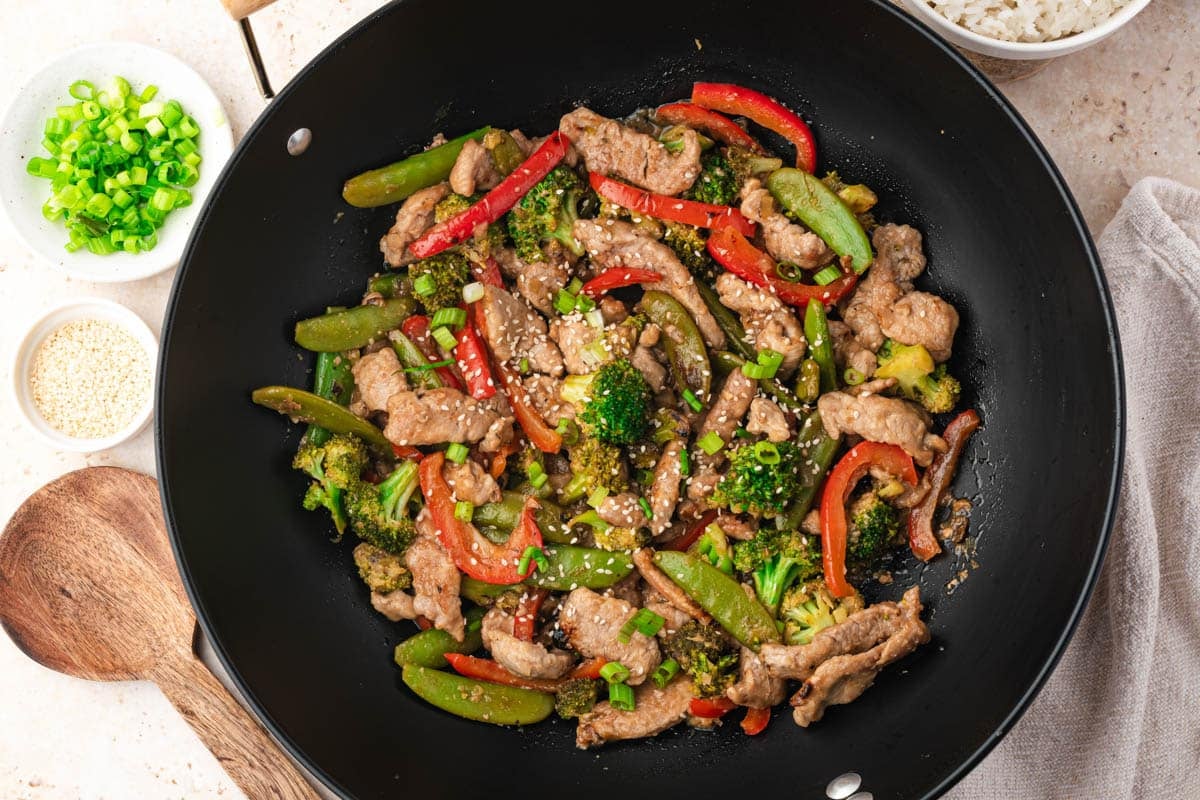 pork stir fry in a skillet with sesame seeds on top