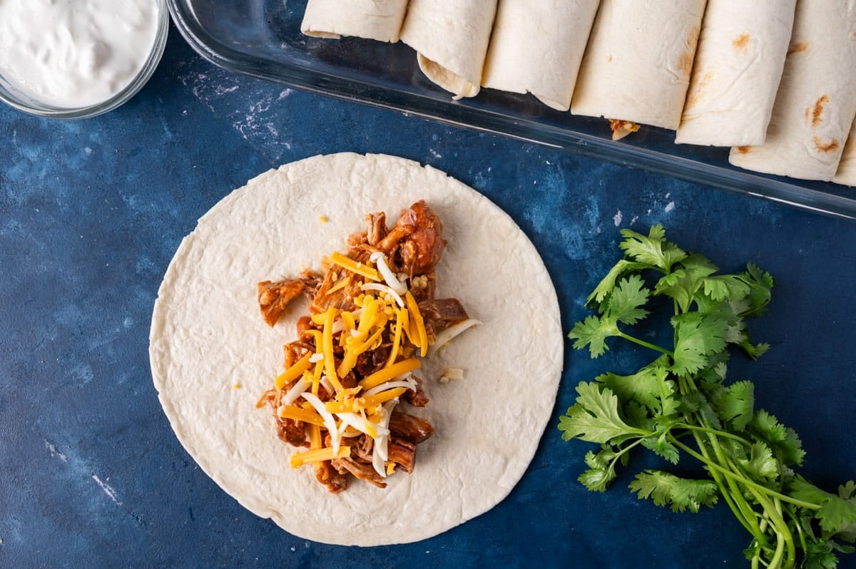 a tortilla with pulled pork and cheese on top of it