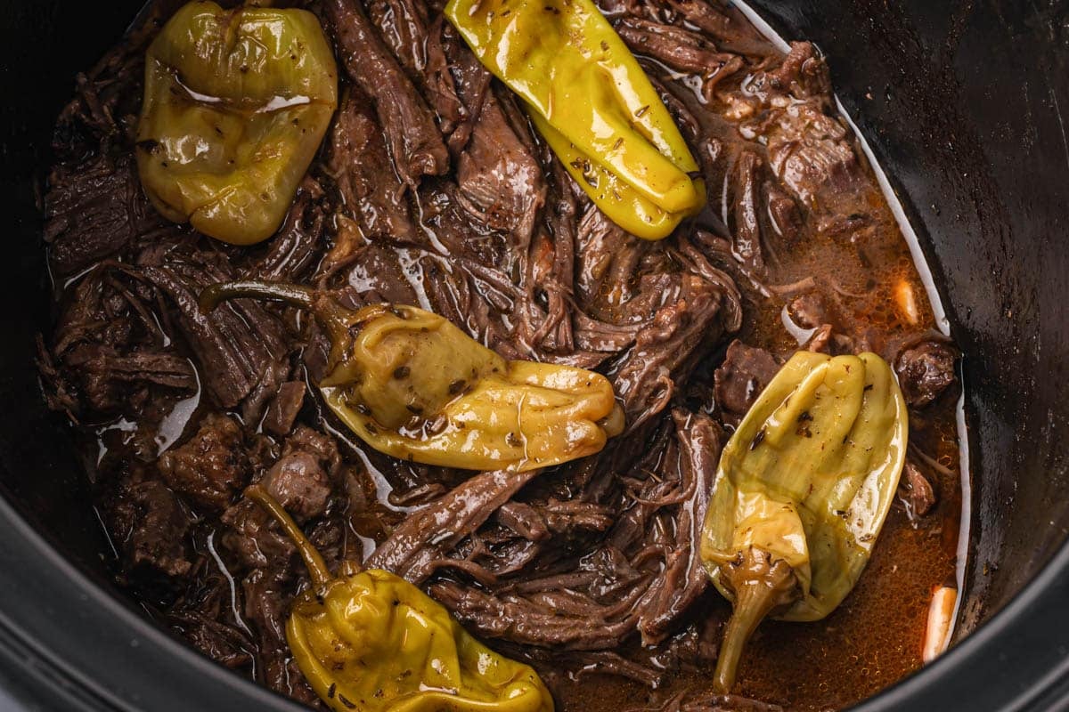 closeup of pot roast with pepperocinis in a slow cooker