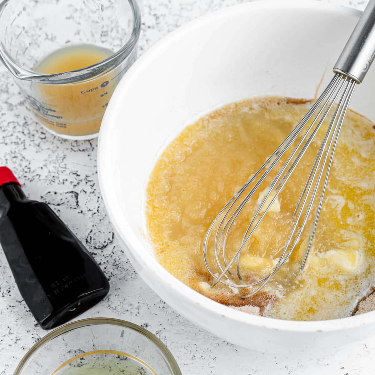 a mixing bowl with cake ingredients and a whisk inside it