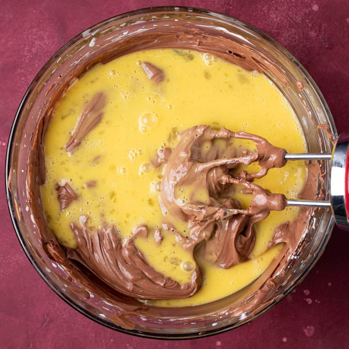 mixing eggs into chocolate cheesecake mixture