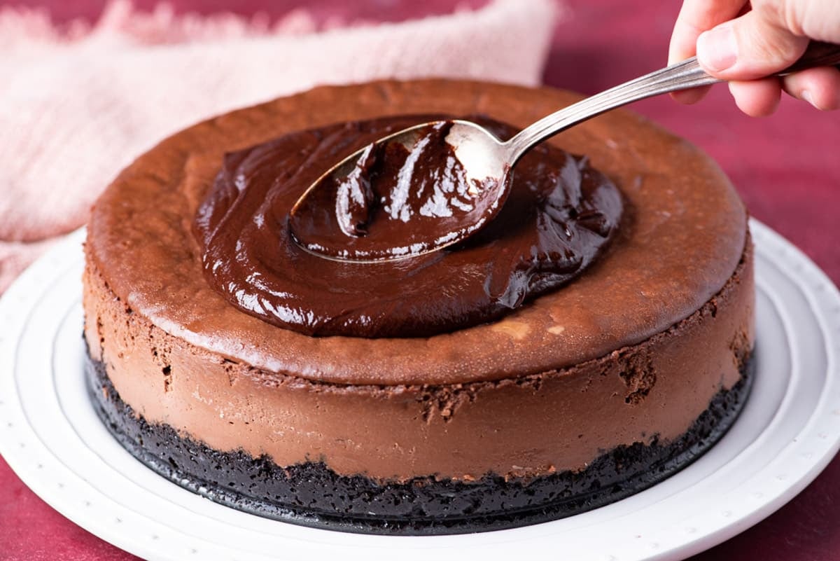 spooning ganache on a cheesecake