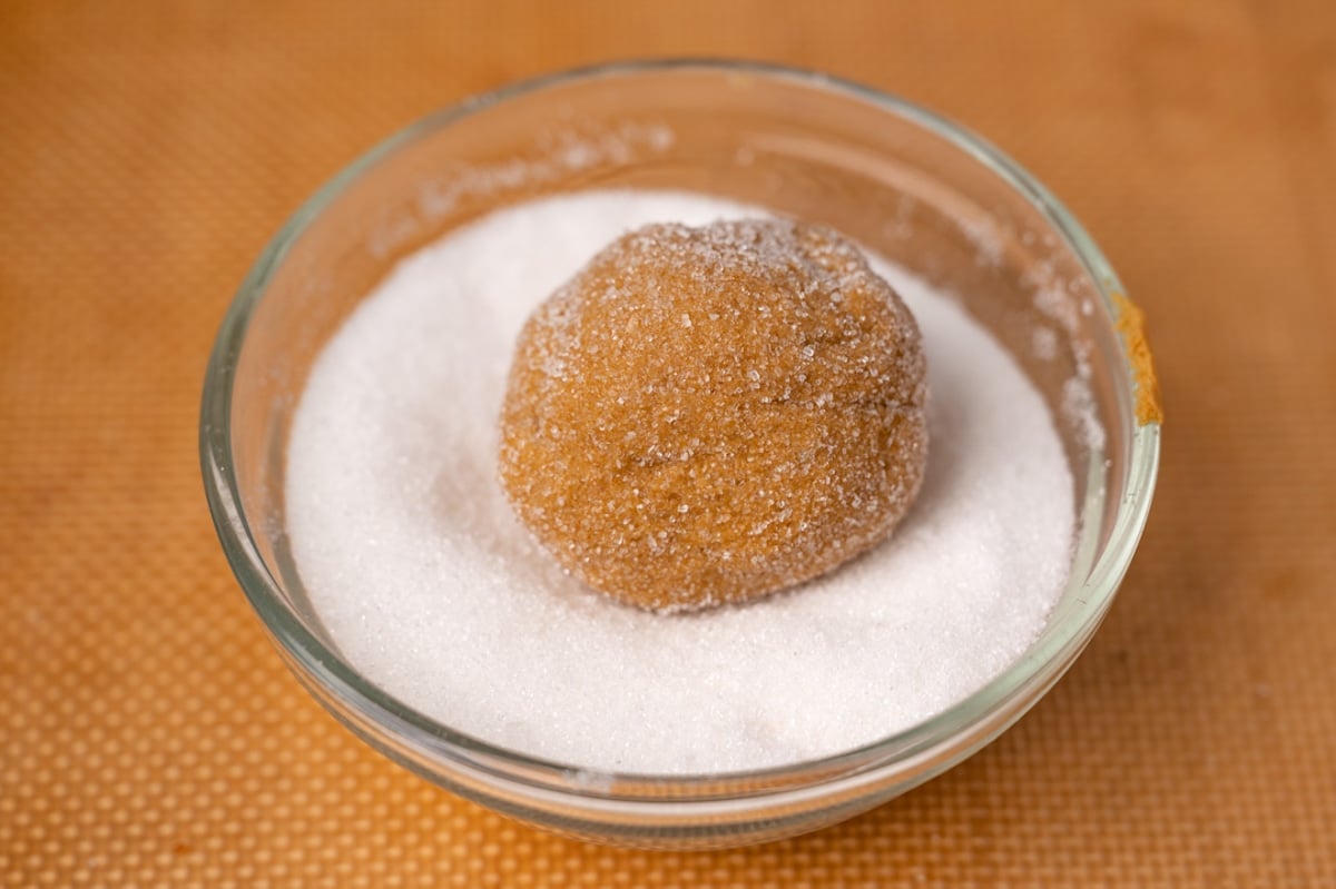 a ball of molasses dough in a bowl of sugar