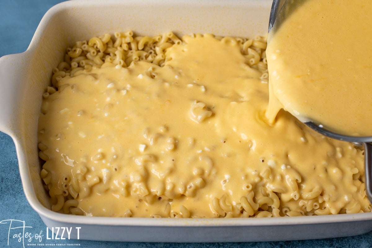 cheese pouring over elbow macaroni in a casserole dish