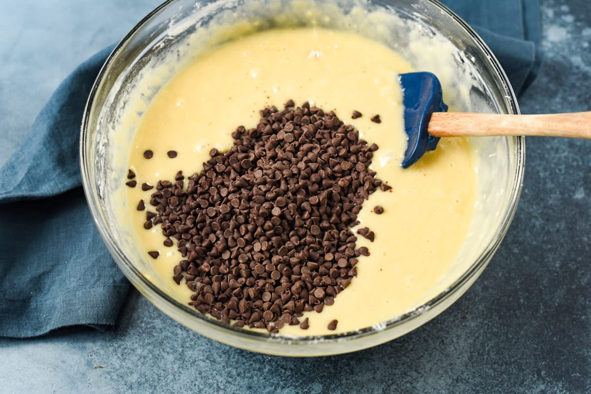 chocolate chips over muffin batter in a bowl